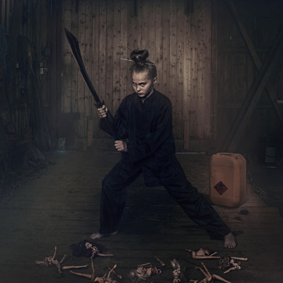 Eirill står med sverd på en låve for portrettfotografering